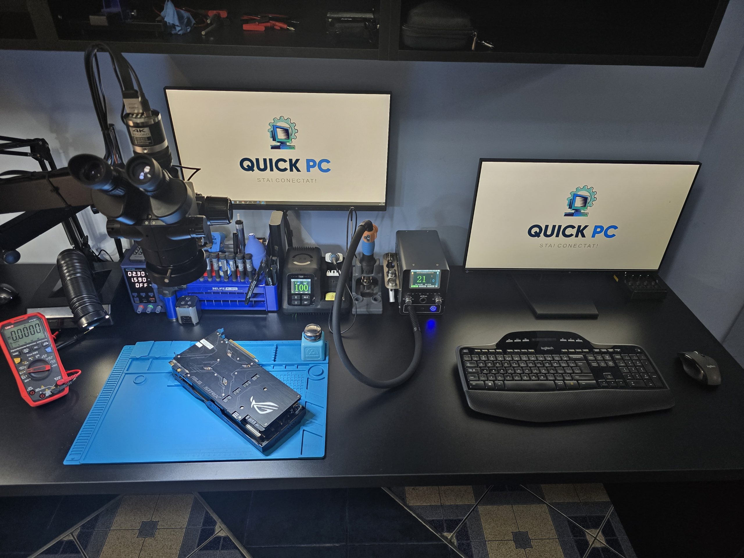 Atelier Quick-PC Focșani - stație de reparații cu microscop, multimetru și placă video pe masa de lucru